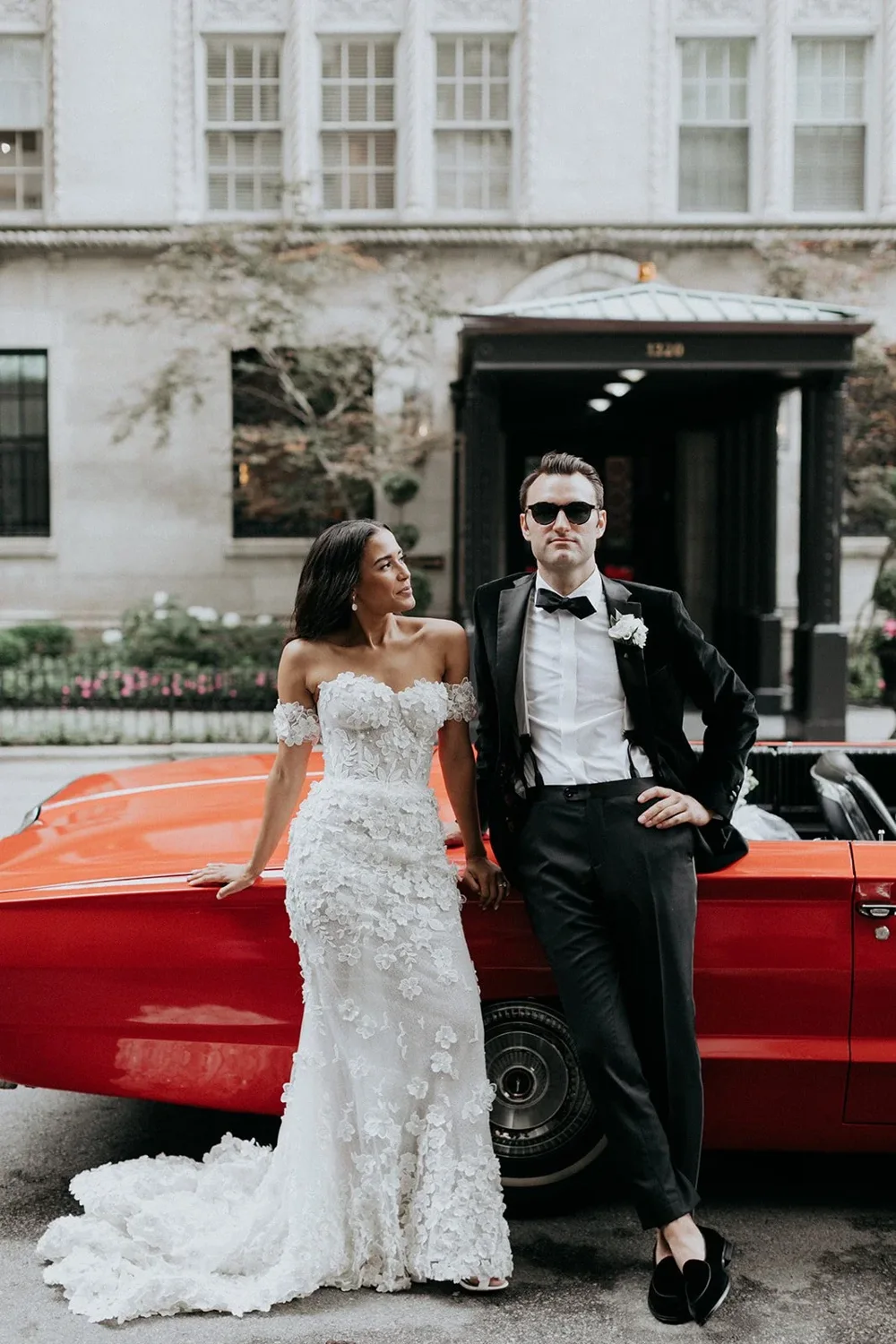 Newlyweds beside a red classic car