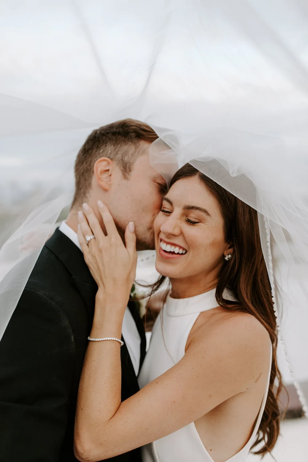 A joyful moment together beneath the wedding veil